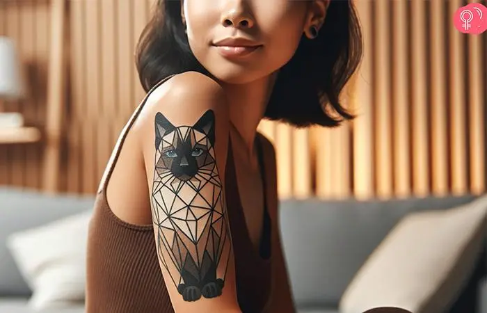 A woman with a geometric Siamese cat tattoo on the upper arm with blue gray eyes