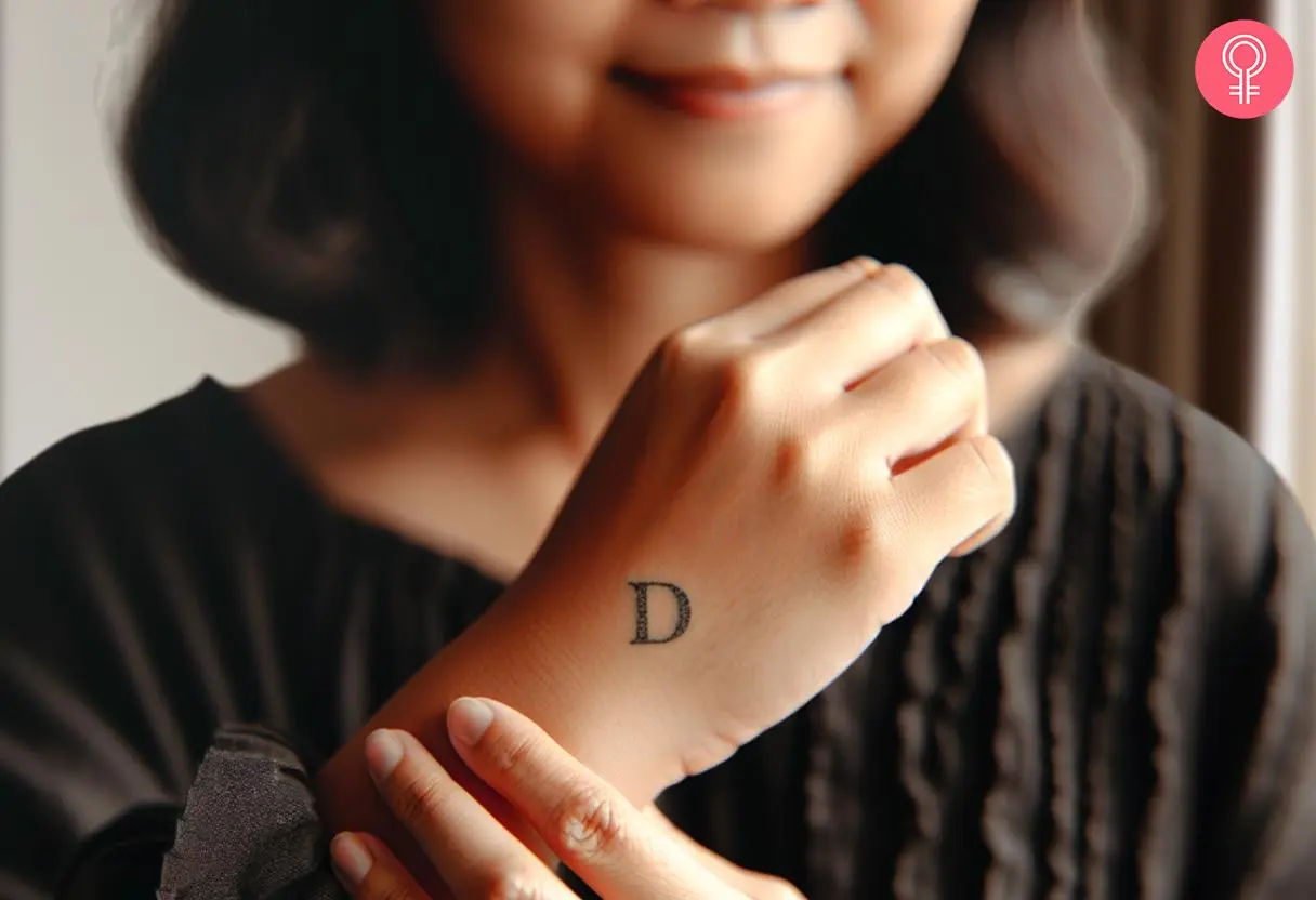 Girl with an uppercase D tattoo on the hand.