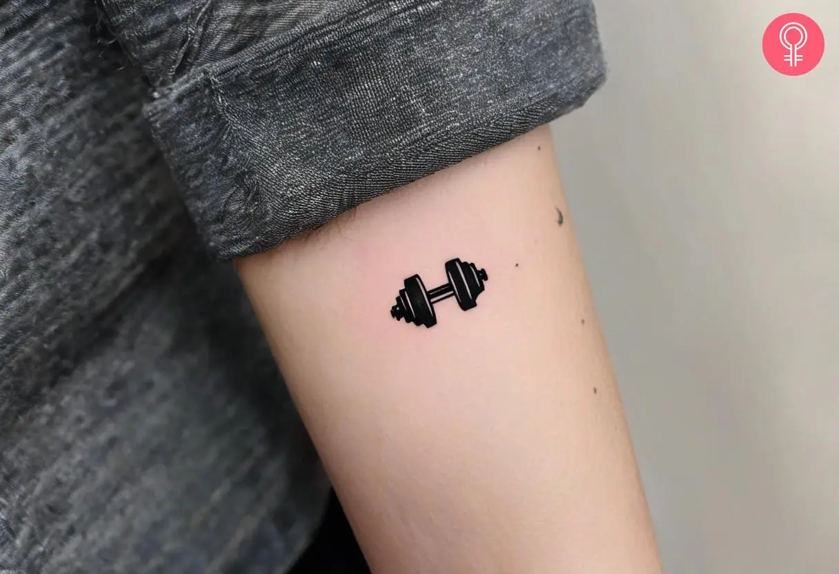 Minimalist gym dumbbell tattoo on the arm