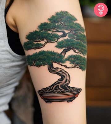 A woman with a colored bonsai tree tattoo on her upper arm