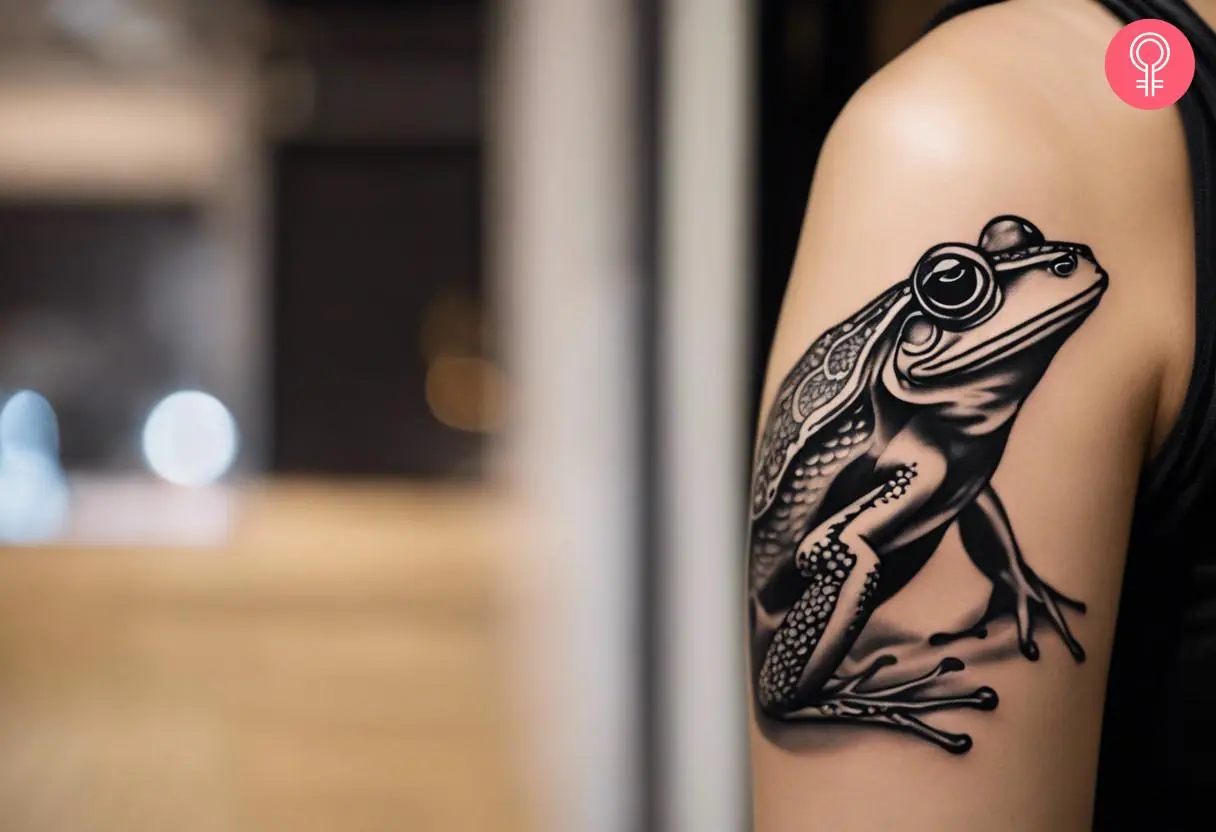 A woman with a black and white Japanese frog tattoo on her upper arm