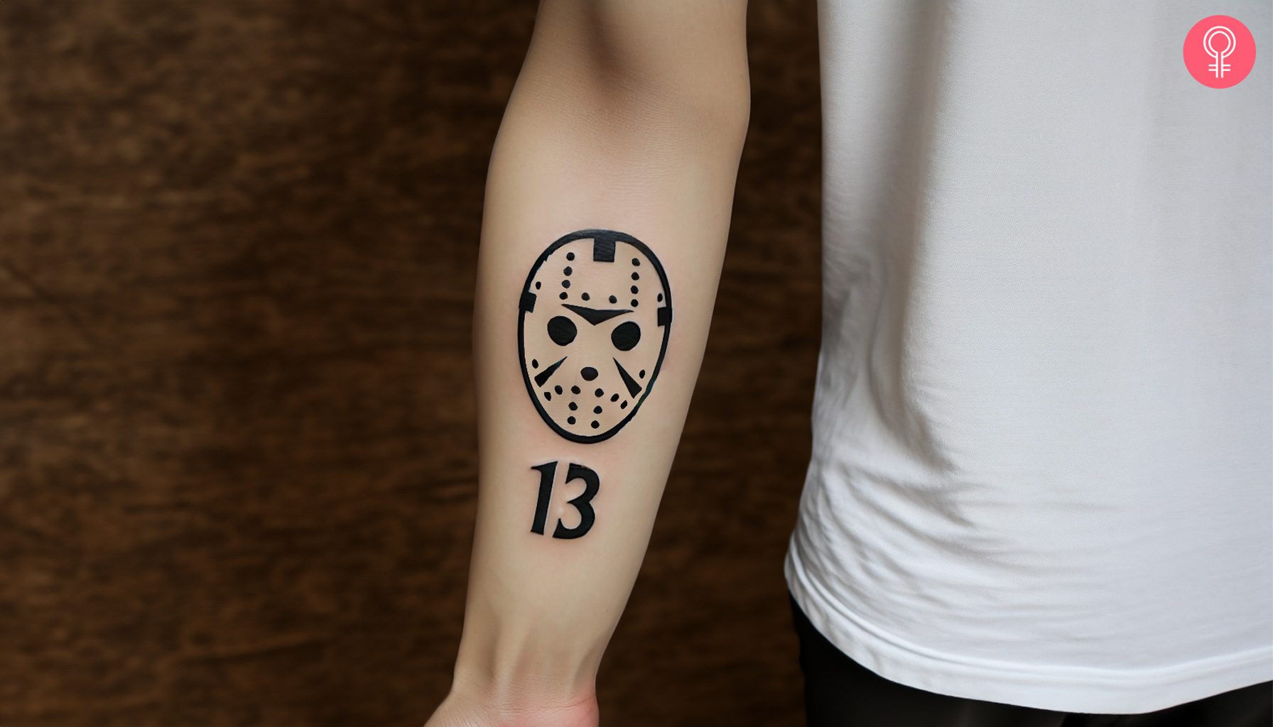 A minimalist Jason mask tattoo with number 13 inked on the forearm