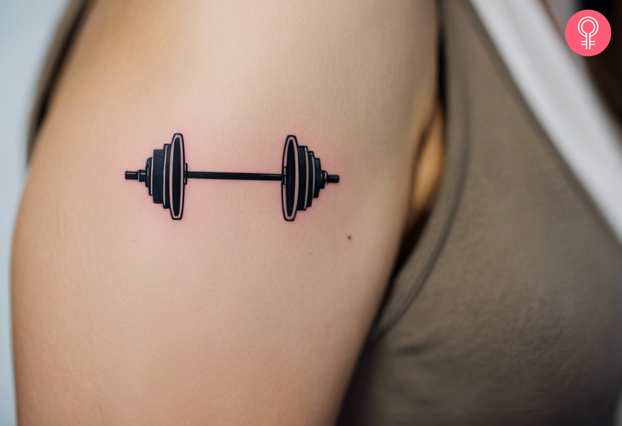 Minimalist barbell tattoo on the upper arm