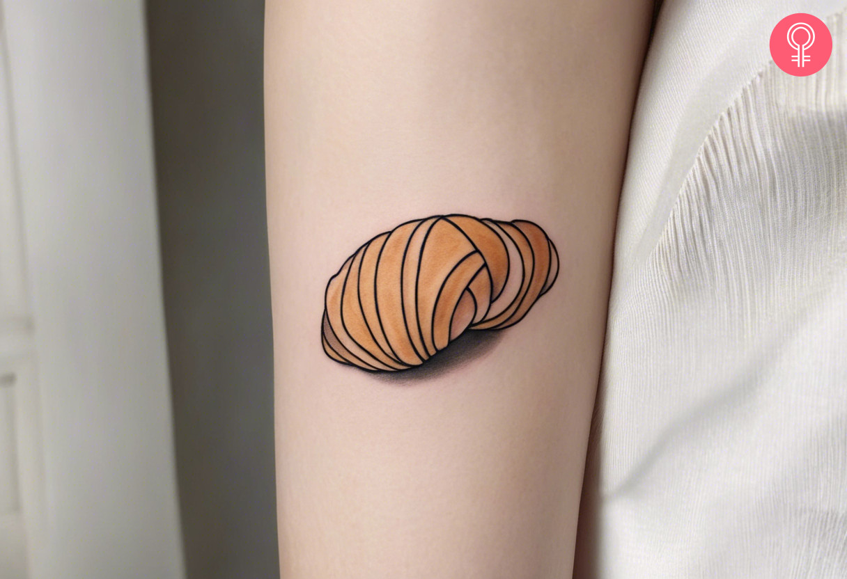 Woman with minimalist croissant tattoo on her outer arm