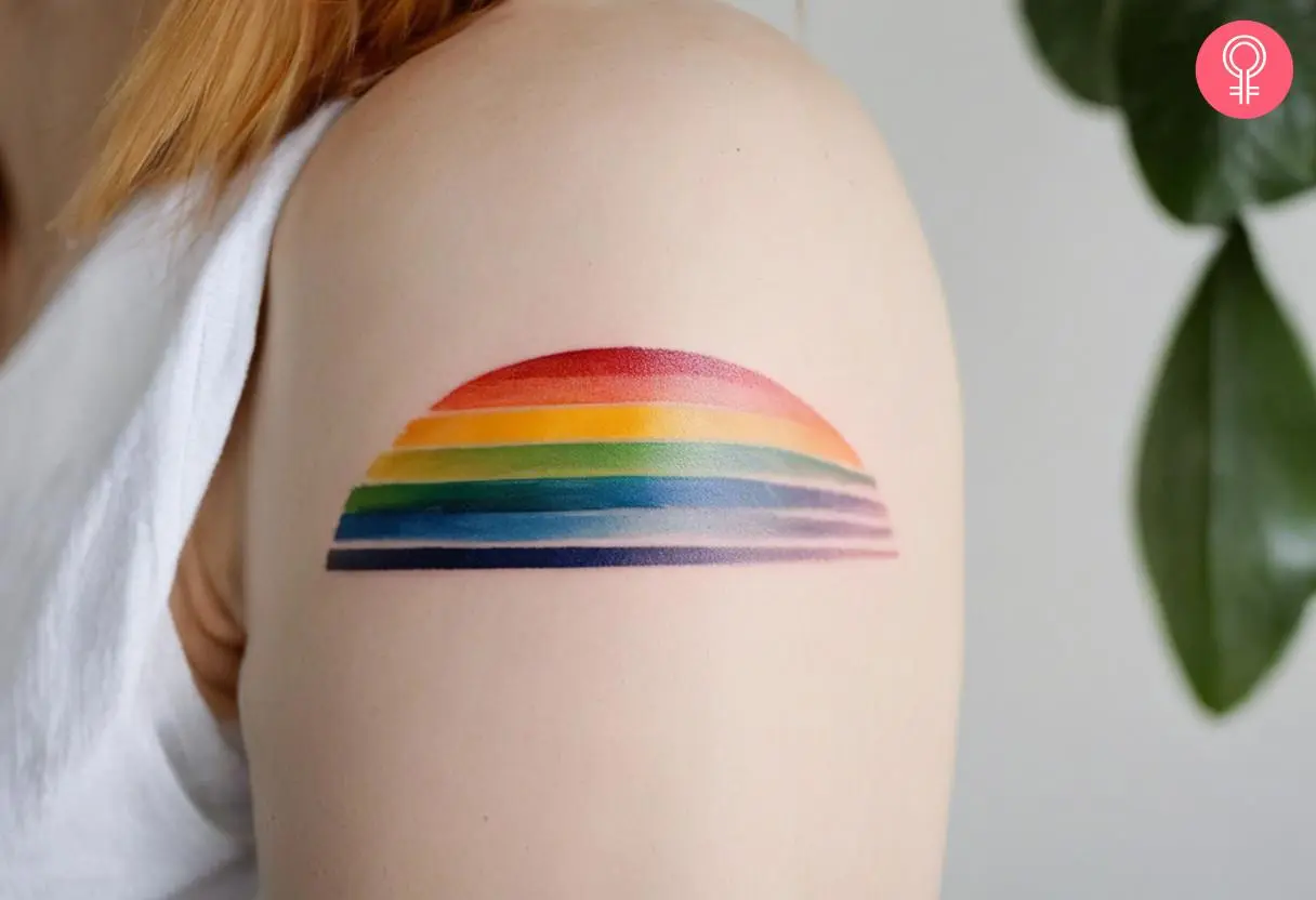 Minimalist rainbow tattoo on a woman’s arm