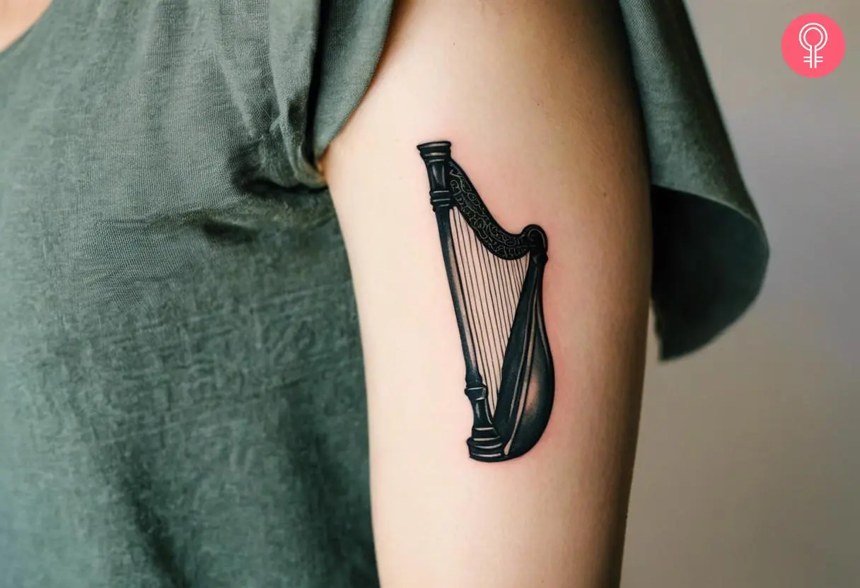 Minimalist harp tattoo on the upper arm