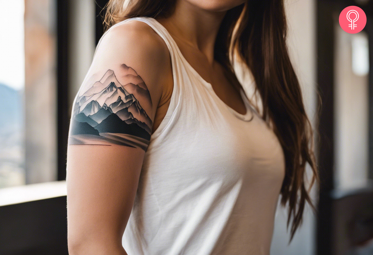 A woman with a minimalist mountain scenery tattoo on her upper arm