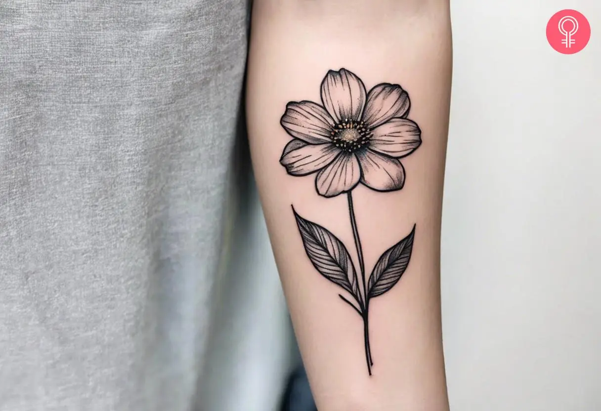 A minimalist cosmos flower inked on the forearm