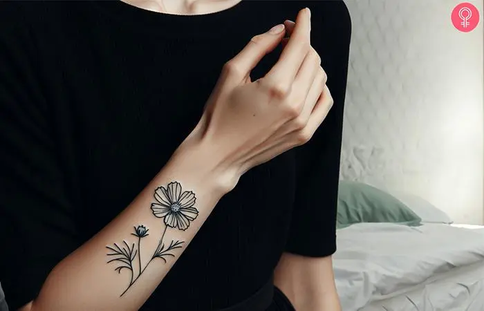 A line art cosmos flower inked on the forearm