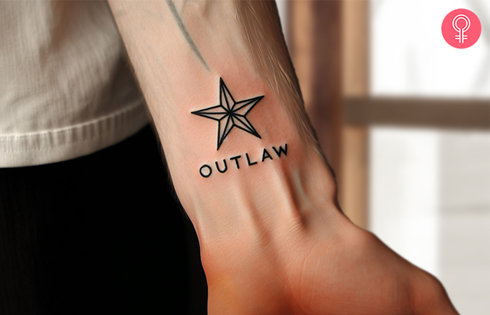 An outlaw text tattoo with a star inked on the wrist