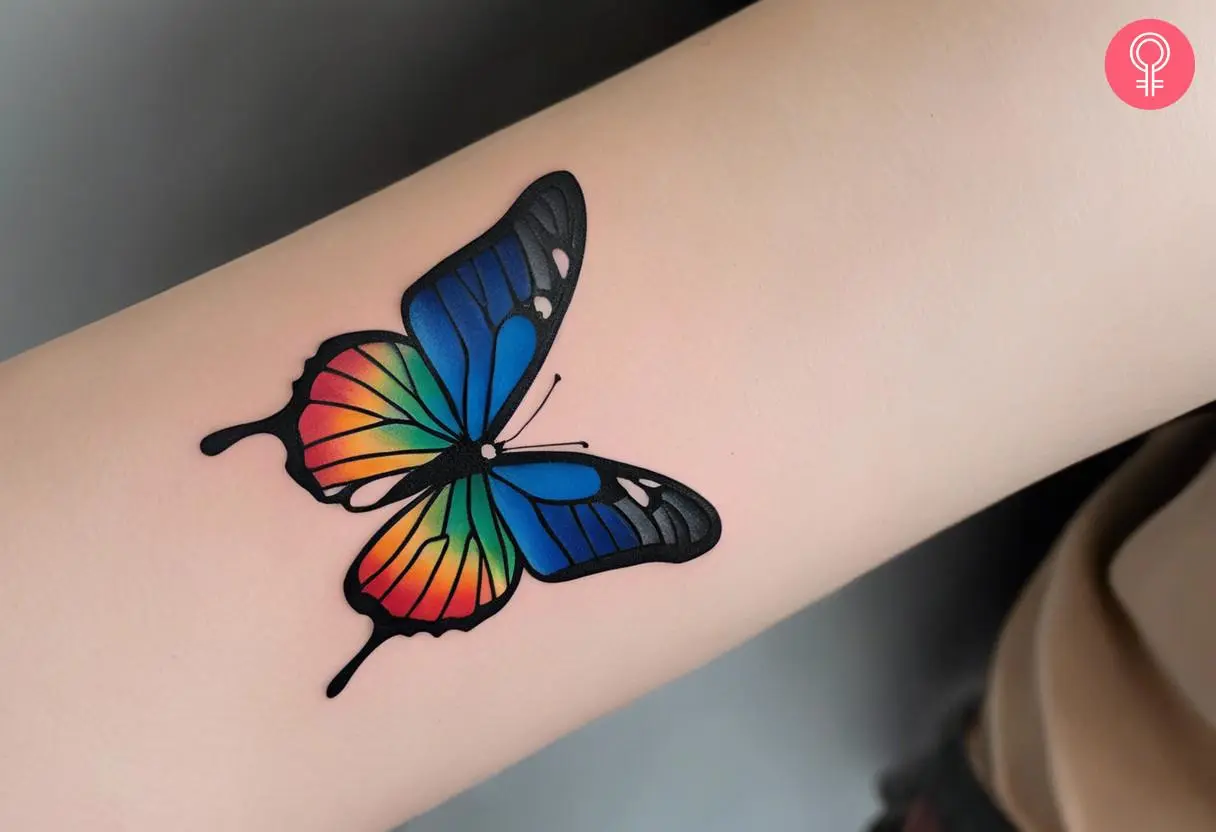 A rainbow butterfly tattoo on the forearm