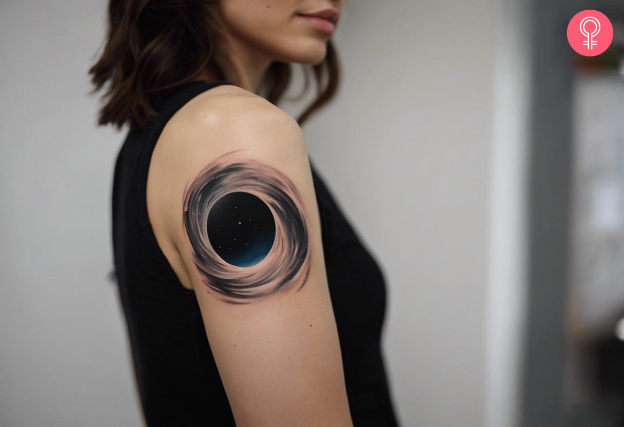 A woman with a realistic black hole tattoo on her upper arm