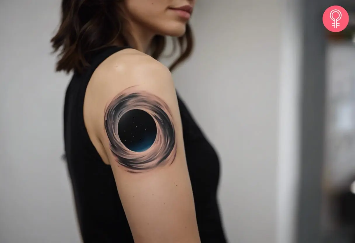 A woman with a realistic black hole tattoo on her upper arm