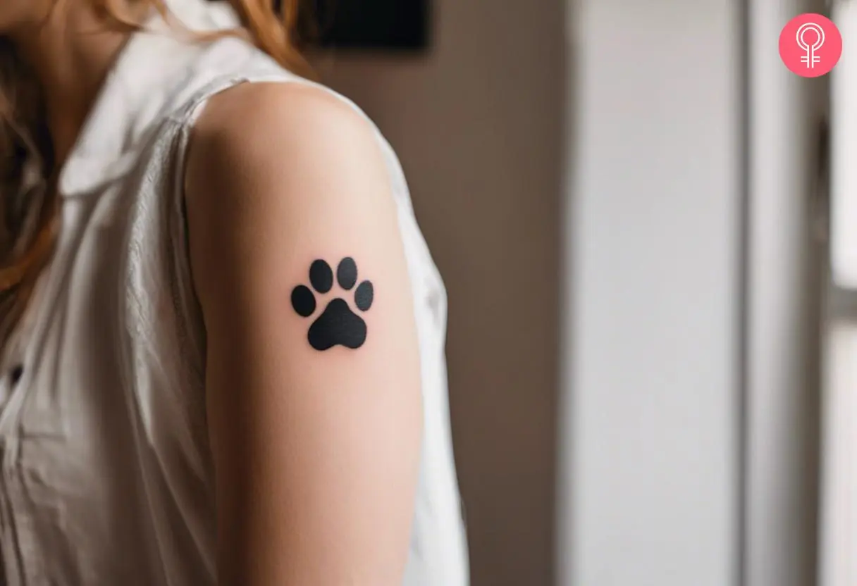 A woman with a black Shih Tzu paw print tattoo on her upper arm