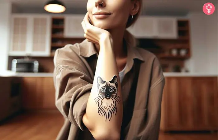 A woman with a Siamese cat forearm tattoo with blue eyes