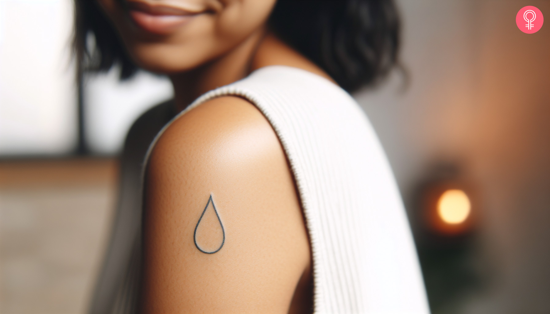 A woman with a simple water drop tattoo on her upper arm