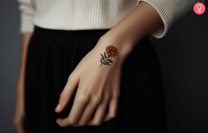 A minimalist marigold flower inked on the hand near thumb