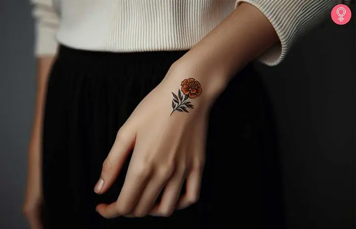 A minimalist marigold flower inked on the hand near thumb