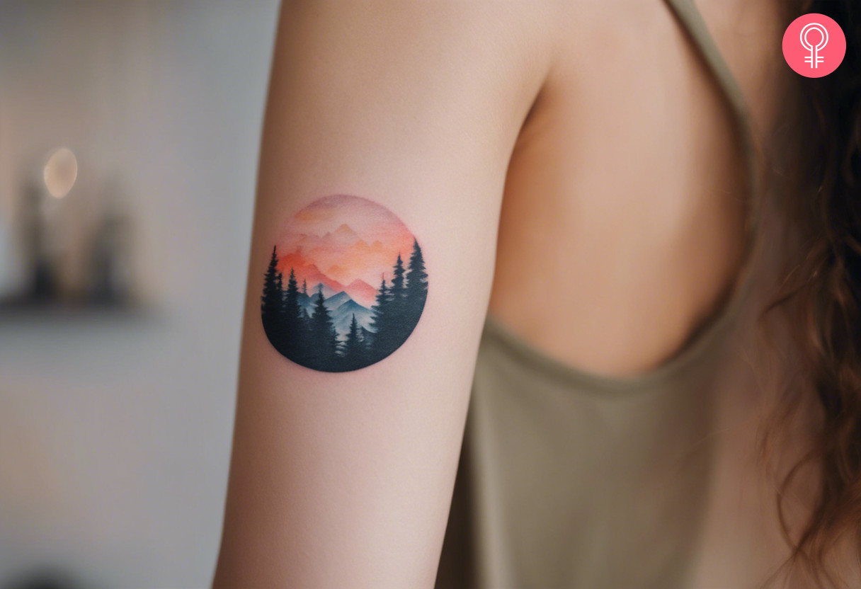 A woman with a small, colored sunset and mountains scenery tattoo on her upper arm