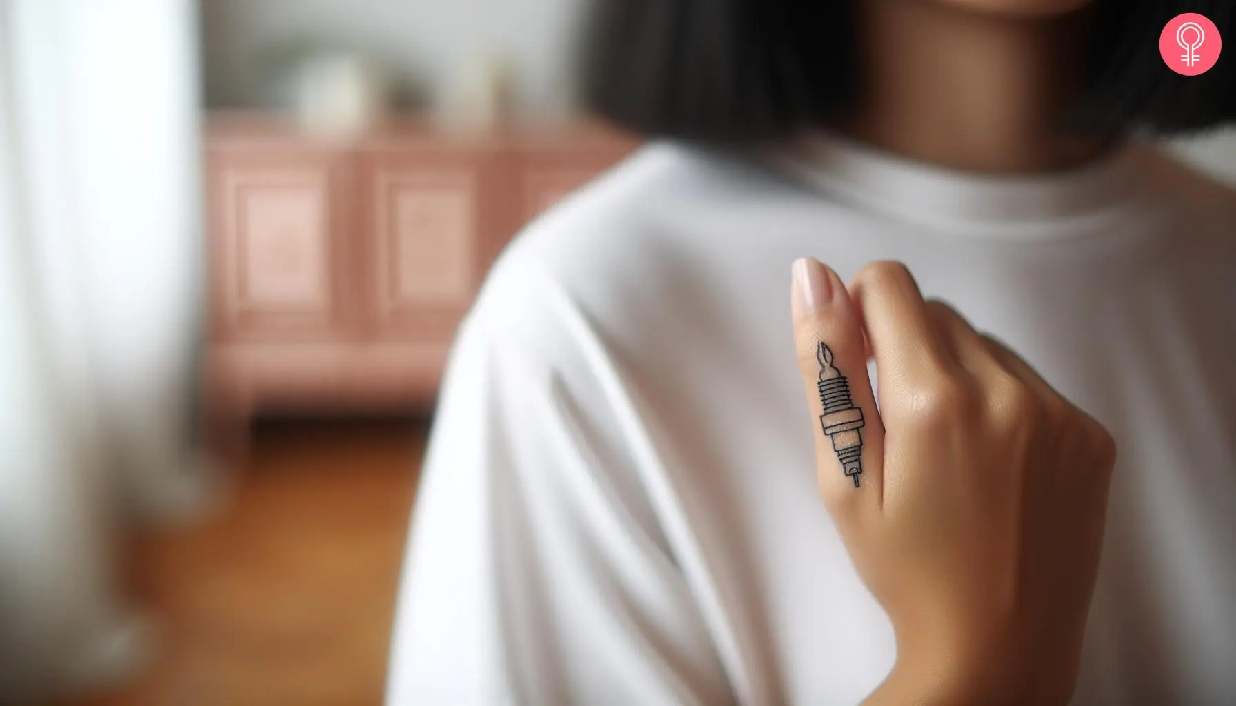 A woman with a small spark plug tattoo on her finger