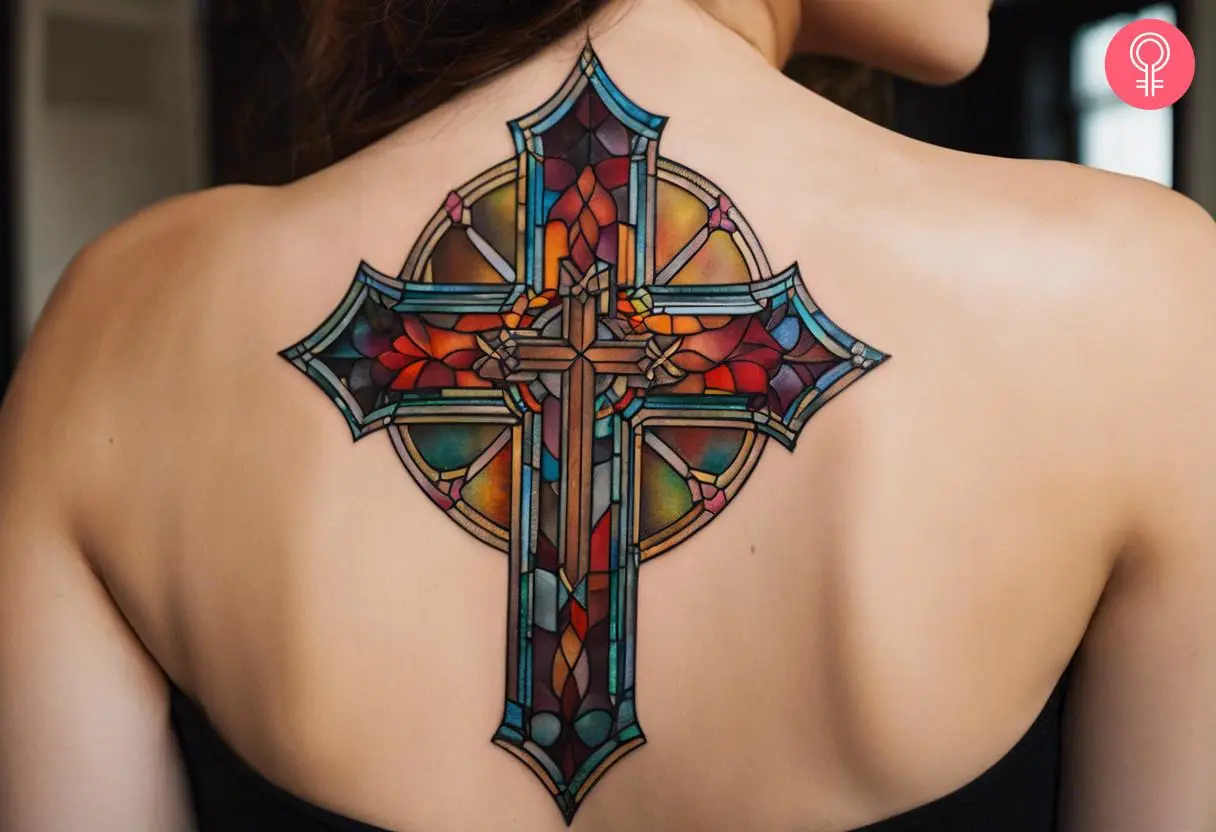 A stained glass cross tattoo on the upper back