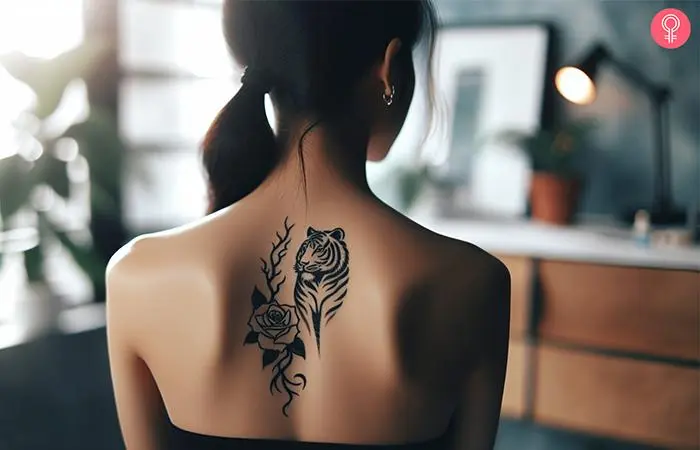 A woman with a black, minimalist tiger rose tattoo on her upper back