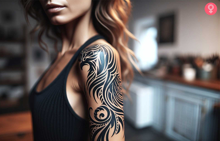 A woman with a black tribal phoenix bird tattoo on her upper arm