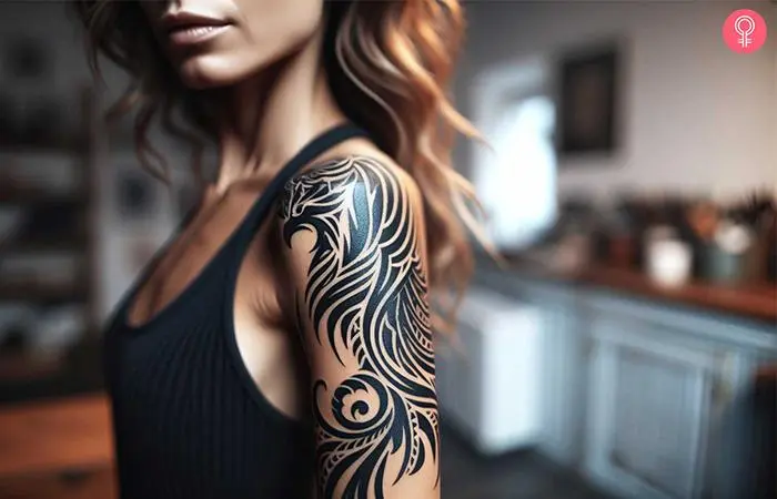 A woman with a black tribal phoenix bird tattoo on her upper arm