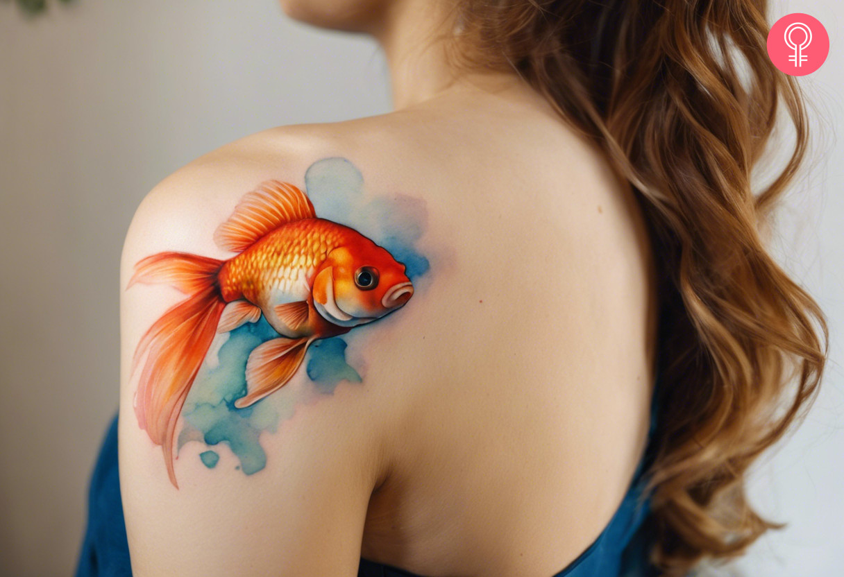 A watercolor goldfish tattoo on a woman’s shoulder