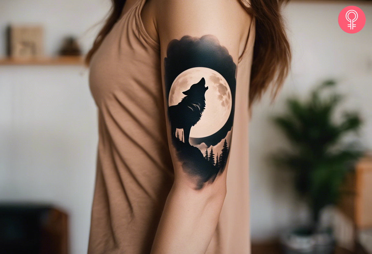 A woman with a minimalist wolf and moon scenery tattoo on her upper arm