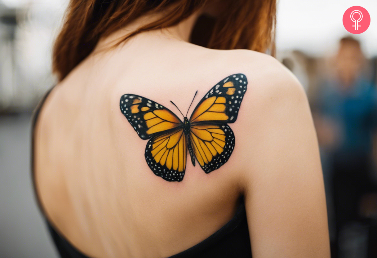 A woman with a vibrant yellow and black butterfly tattoo on her upper back