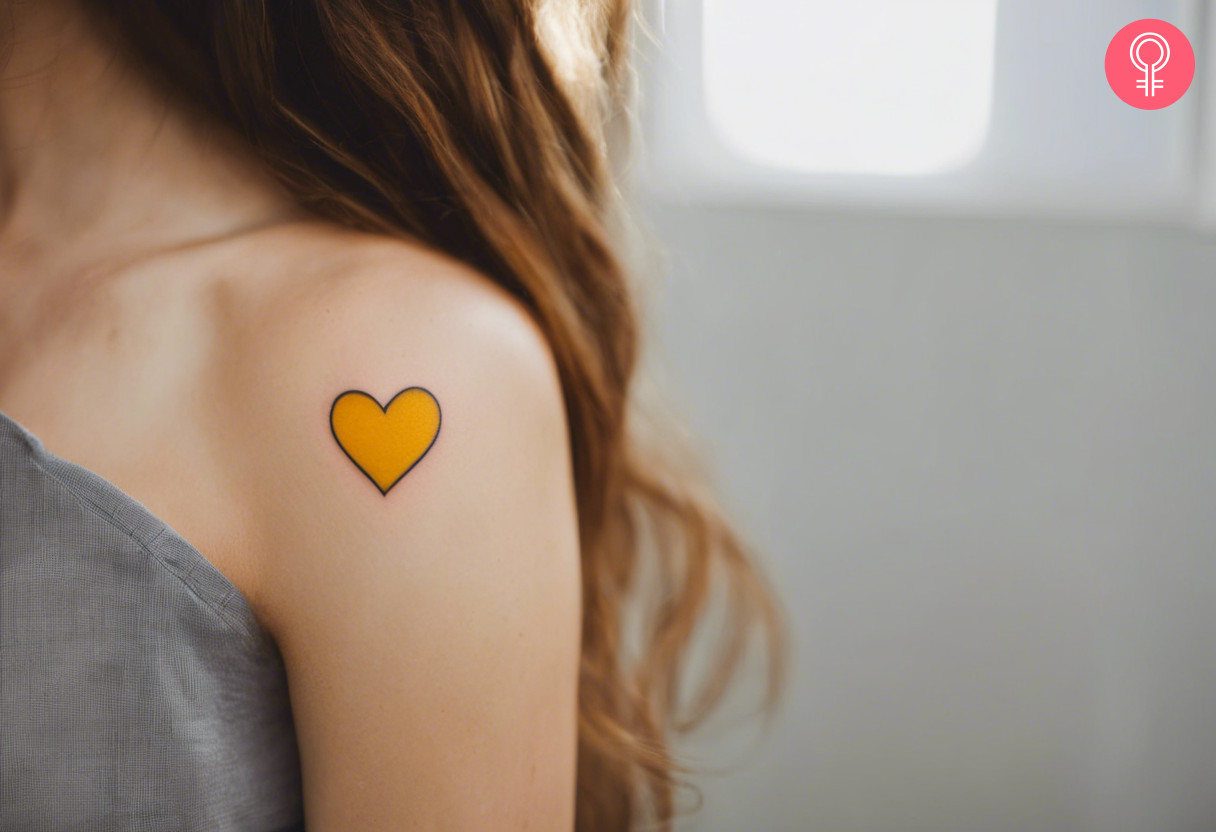 A woman with a vibrant yellow heart tattoo on her shoulder