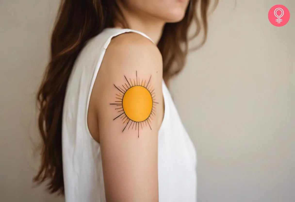 A woman with a vibrant yellow sun tattoo on her upper arm