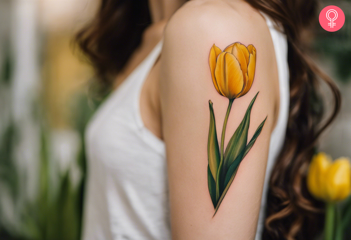 A woman with a vibrant yellow tulip tattoo on her upper arm