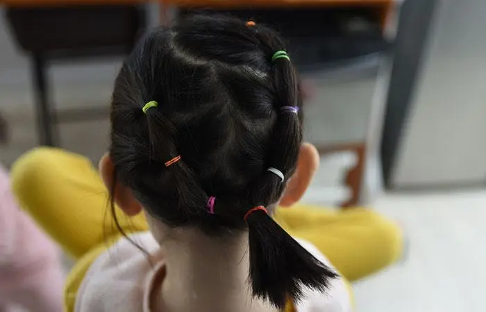 A little girl with a short rubber band hairstyle