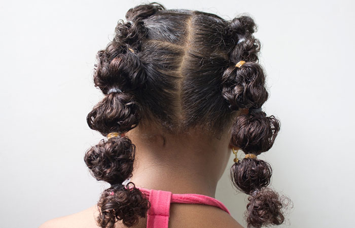 A little girl with  curly hair rubber band hairstyle