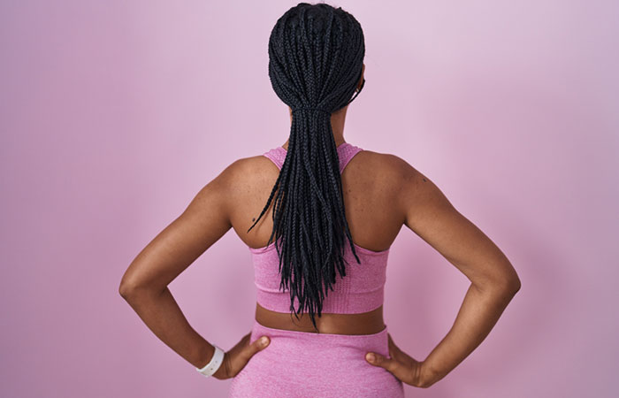 A protective braided hairstyle tied into a low ponytail for softball