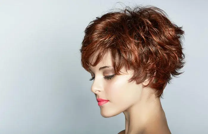 A woman with a long pixie cut on her dark brown hair with copper highlights