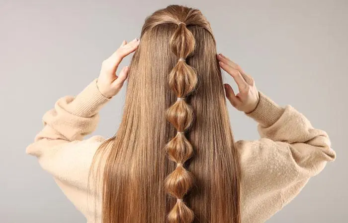 A woman with a rubber band hairstyle on her straight hair