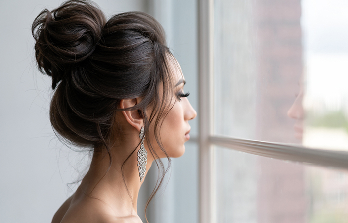 A woman with stunning messy high bun bridesmaid hairstyle