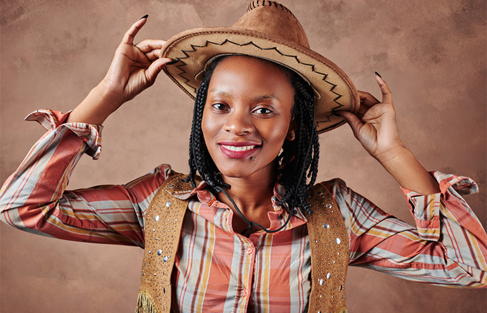 A woman with short length box braids wearing a cowboy hat