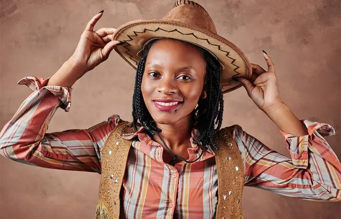 A woman with short length box braids wearing a cowboy hat