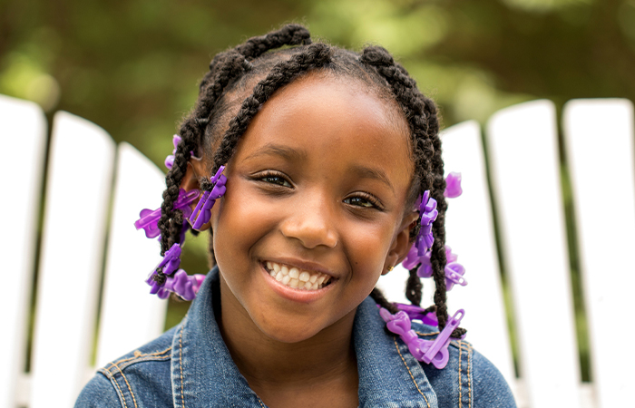 A little girl sporting a braided weave hairstyle