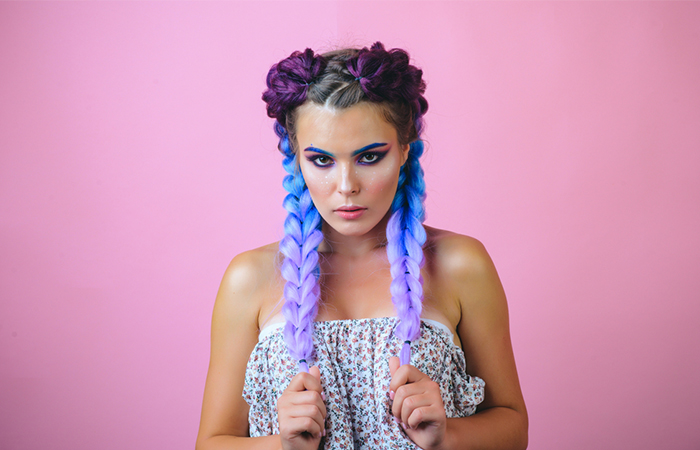 A woman with two braids with blue and purple Kanekalon strands