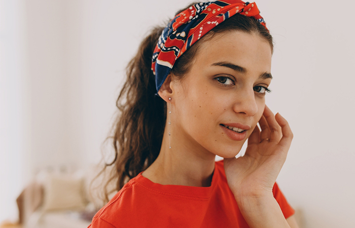 A woman with a messy ponytail and a bandana wrapped over the forehead 