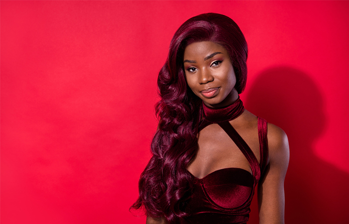 A woman sporting a vibrant plum wavy weave hairstyle