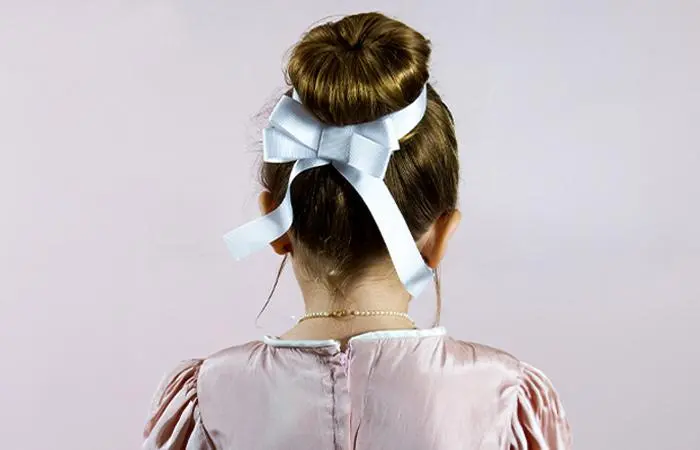 A kid with a flower girl bun hairstyle