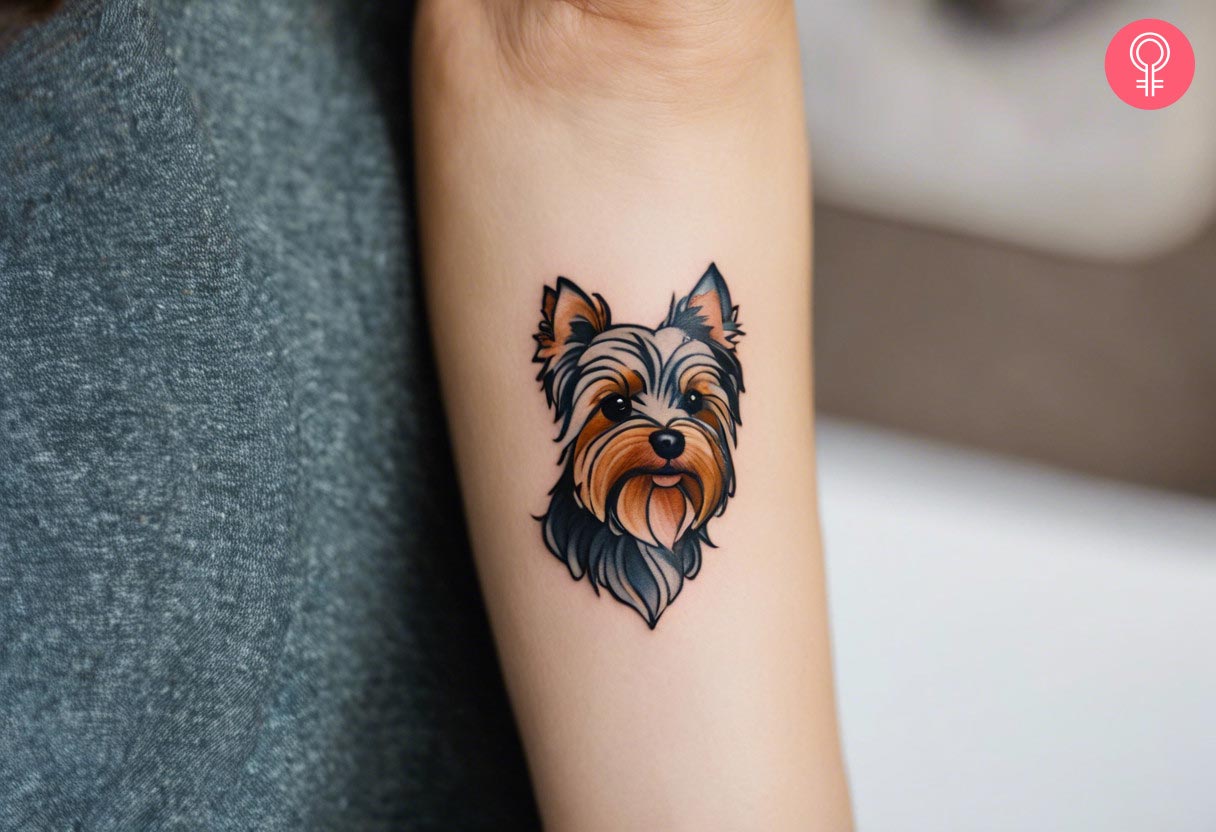 A woman with a minimalist Yorkshire terrier tattoo on her forearm