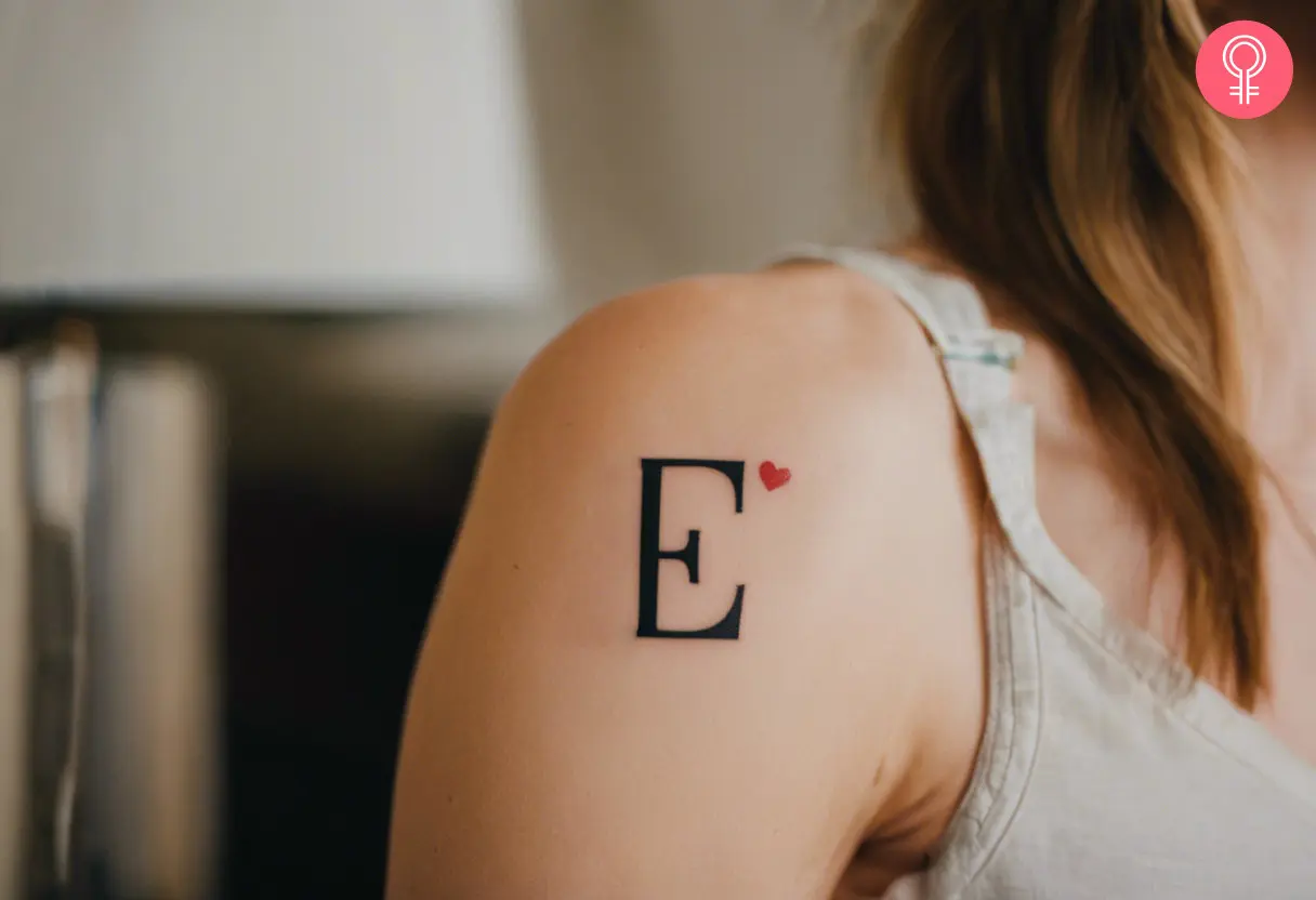 Letter E tattoo with heart on a woman’s bicep