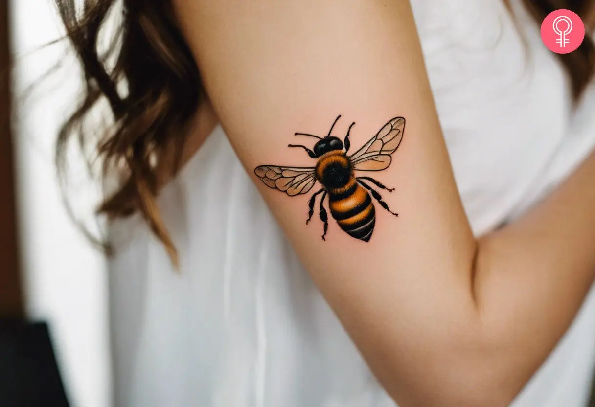 A woman with a traditional honey bee tattoo on her bicep